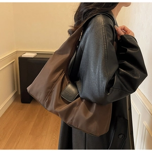 Detail view of large coffee nylon hobo bag on shoulder showing drape and wide strap
