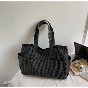 Detail view of plaid tote bag featuring side pockets and large capacity storage design