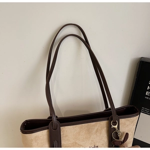 Detail of beige suede tote bag with brown leather trim and fine embroidery texture