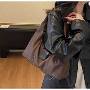 Detailed close-up of brown nylon hobo bag with black leather flap and logo branding