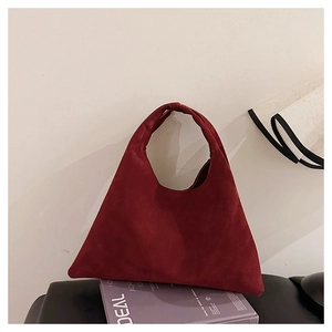 Detail of red minimalist triangular tote bag in matte suede on decorative books