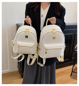 Close-up of white tweed backpack featuring gold-tone zippers and elegant metallic logo