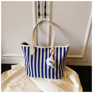 Detail of blue and white striped canvas tote bag with plush doll charm on handle