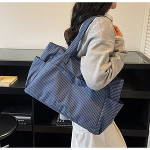 Detail of navy plaid canvas tote bag showing side pocket and spacious design for daily use