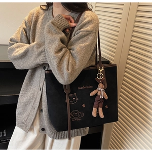 Detail of black suede tote bag with cat embroidery and plush bunny pendant for women