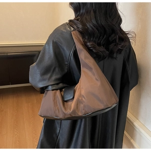 Detail view of brown nylon crescent shoulder bag with black leather strap and trim