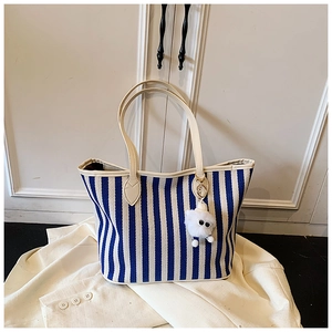 Detail of blue and white striped canvas tote bag featuring a cute white plush bear charm
