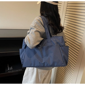 Detail of blue gingham tote bag showing spacious interior and side pocket on the model