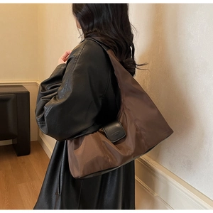 Brown nylon tote bag with black leather flap shown worn on a model's shoulder