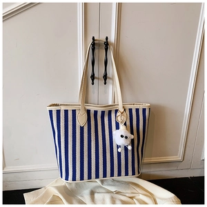 Detail of blue striped canvas tote bag with beige leather trim and sheep plush charm