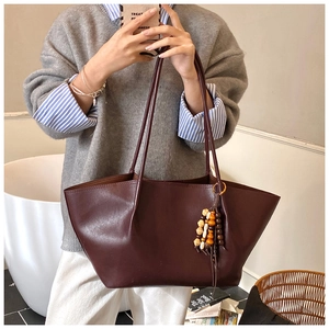 Detail of vintage large burgundy tote bag with beaded tassel in cozy lifestyle setting
