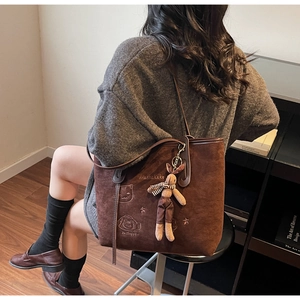 Detail of dark brown suede tote bag with cat embroidery and plush rabbit keychain charm