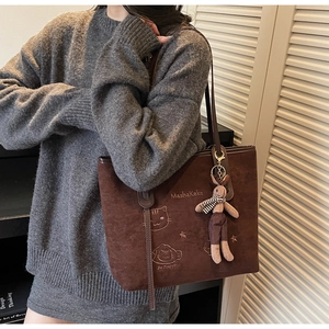 Detail of dark brown suede tote bag featuring cat embroidery and cute rabbit pendant