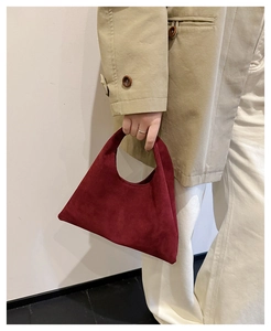 Detail of the dark red suede tote bag showing its unique triangular shape and matte texture