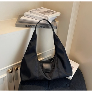 Detail of black nylon hobo bag featuring leather magnetic flap and minimalist strap
