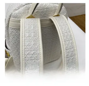 Detail of tweed backpack shoulder strap with gold hardware and reinforced piping