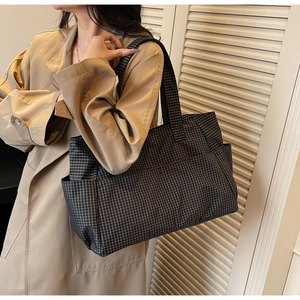 Detail of the large capacity checkered tote bag showing the side pocket and canvas texture