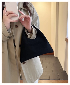 Minimalist black matte geometric tote bag shown on a model with a beige trench coat
