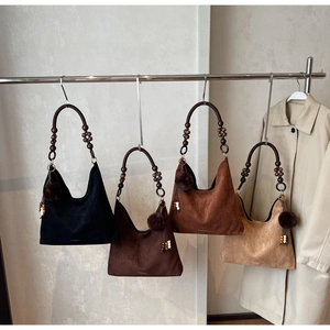 Detail of suede tote bags with wooden bead handles and tassel charms in four colors