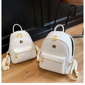 Detailed close-up of white tweed texture and gold hardware on minimalist backpacks
