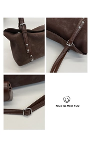 Detail view of dark brown suede bag showing silver rivets and high-quality stitching texture