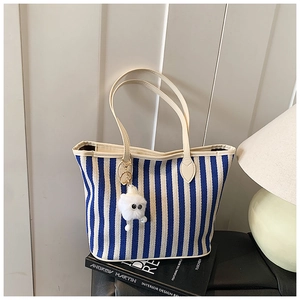 Close-up of blue striped canvas tote bag with cream handles on fashion books