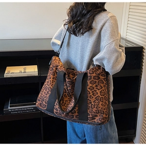 Close-up of leopard print canvas travel tote bag with black wide straps and zipper