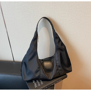 Detail of black nylon crescent shoulder bag featuring leather flap and fashion logo