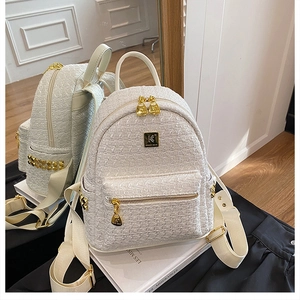Detail of white tweed backpack with gold studs and brand logo in a mirror reflection
