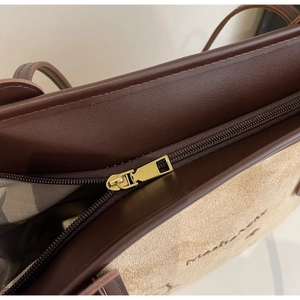 Detail of premium brown leather and beige suede tote bag with gold zipper and embossed logo