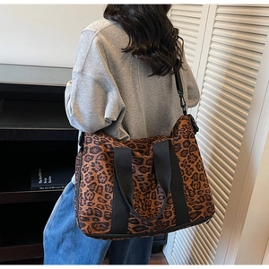 Lifestyle shot of large leopard print canvas travel bag with adjustable shoulder strap