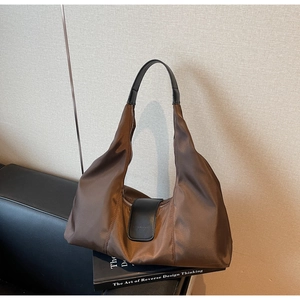 Detail of dark brown nylon crescent bag with black leather accents on a sofa