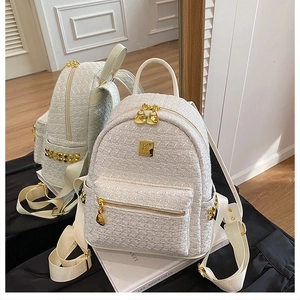 Detail of white tweed backpack with gold heart zipper and polished metal hardware accents