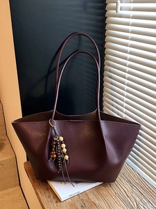 Vintage burgundy tote bag with wood bead tassel on a wooden bench with soft lighting