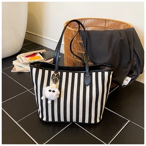 Detail of black and white striped canvas tote bag with leather handles and cloud charm