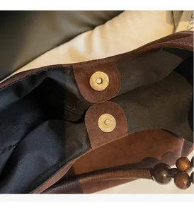 Detail of vintage brown suede tote bag with golden magnetic buckles and wood bead strap