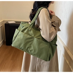 Detail of green plaid tote bag with large front pocket and wide handle for daily use