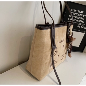 Detailed embroidery of cat motif and brand lettering on beige suede tote bag surface