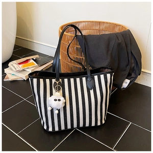 Close-up of black and white striped canvas tote bag with a cute fluffy lamb pendant charm