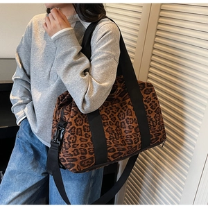 Lifestyle shot of large leopard print travel bag with adjustable black shoulder strap