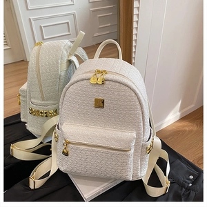 Detail view of white tweed backpack featuring gold studs and dual metal zippers