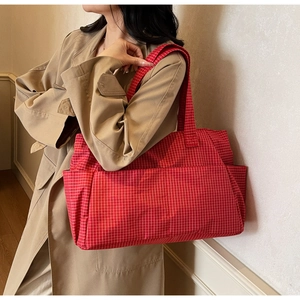 Detail of red checkered tote bag showing the side pocket and durable fabric texture