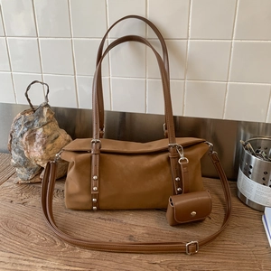 Detailed texture of brown suede tote bag with silver rivets and matching small pouch