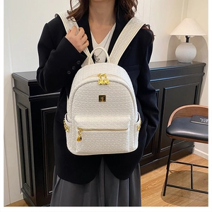 Close-up of a cream tweed backpack featuring gold metal hardware and a wide woven strap