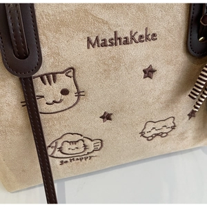 Close-up of beige suede tote bag featuring exquisite cat embroidery and leather strap detail