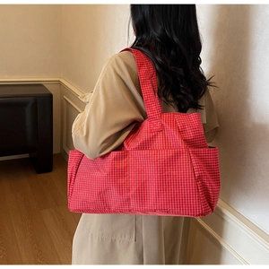 Close-up of red and white plaid canvas tote bag with functional front pockets