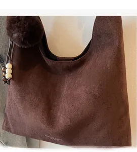 Detail of vintage matte brown tote bag showing suede texture with decorative fur ball and beads