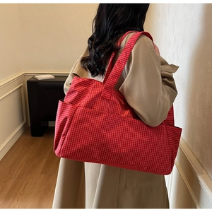 Detail view of large red checkered tote bag with side pocket shown on a model