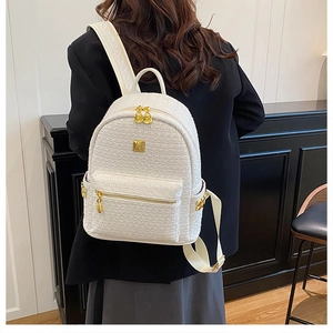Detail view of a white tweed backpack with gold zippers shown on a model