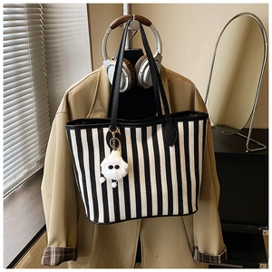 Close-up of black and white striped canvas tote bag with a cute white plush charm detail